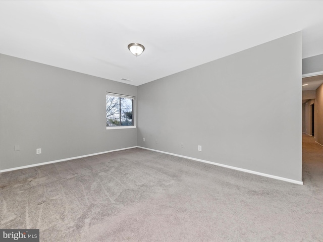 carpeted spare room with visible vents and baseboards