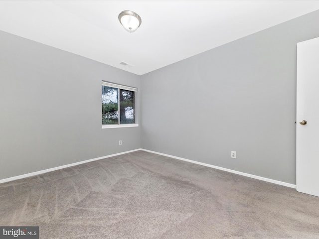 spare room featuring carpet flooring and baseboards