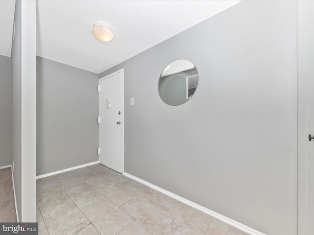 empty room featuring baseboards and light tile patterned floors