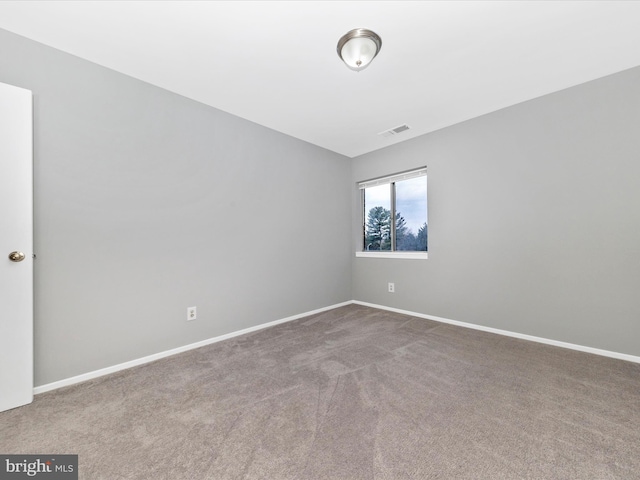 unfurnished room with carpet floors, visible vents, and baseboards