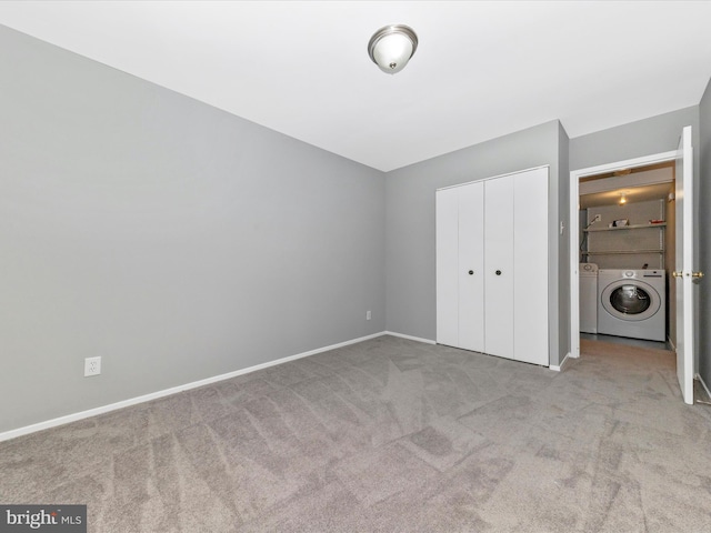 unfurnished bedroom featuring a closet, independent washer and dryer, carpet flooring, and baseboards