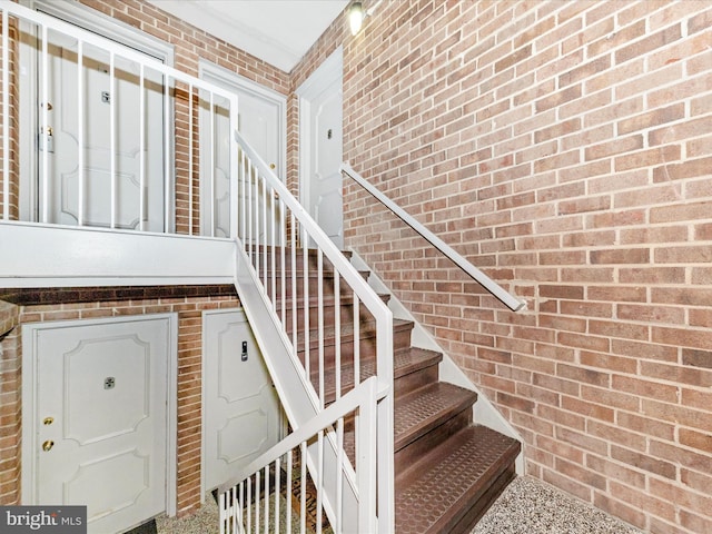 stairway featuring brick wall