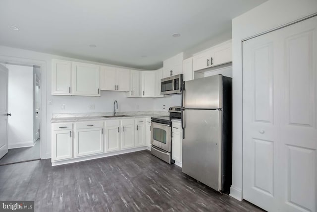 kitchen with dark wood finished floors, appliances with stainless steel finishes, light countertops, white cabinetry, and a sink