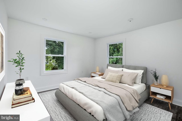 bedroom featuring multiple windows, baseboards, and dark wood-type flooring