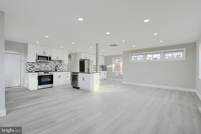 kitchen with visible vents, backsplash, open floor plan, appliances with stainless steel finishes, and white cabinets