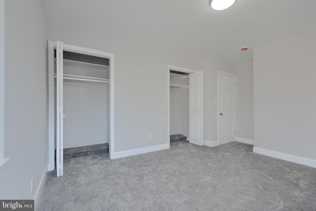 unfurnished bedroom with light carpet, baseboards, and multiple closets