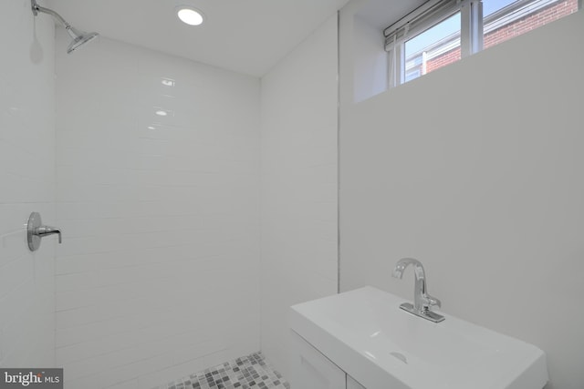 bathroom featuring a tile shower, a sink, and recessed lighting