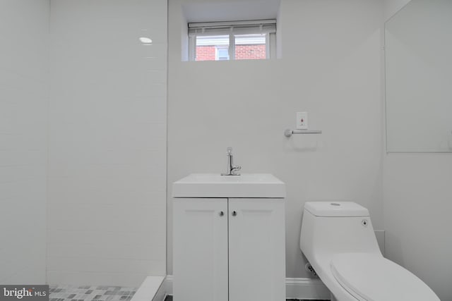 bathroom with tiled shower, vanity, and toilet