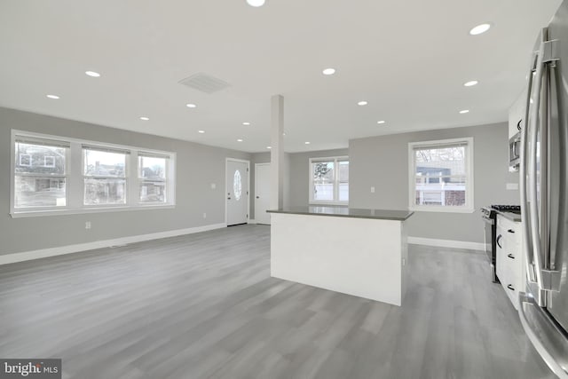 kitchen featuring wood finished floors, a kitchen island, recessed lighting, white cabinets, and appliances with stainless steel finishes