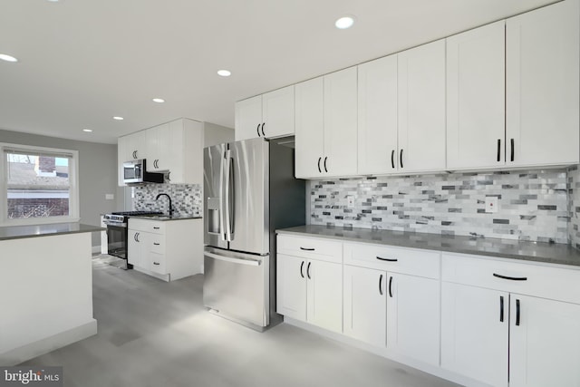 kitchen featuring white cabinets, dark countertops, stainless steel appliances, backsplash, and recessed lighting