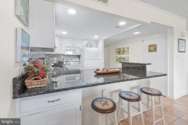 kitchen with visible vents, white cabinets, dark stone counters, white appliances, and a peninsula