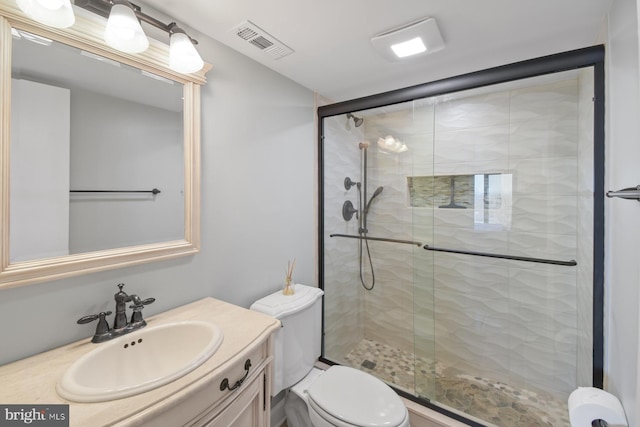 bathroom featuring toilet, vanity, a shower stall, and visible vents