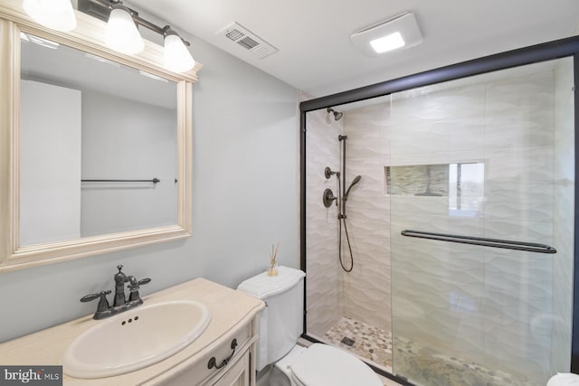 bathroom with a stall shower, visible vents, vanity, and toilet