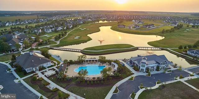 aerial view at dusk with a water view, a residential view, and golf course view