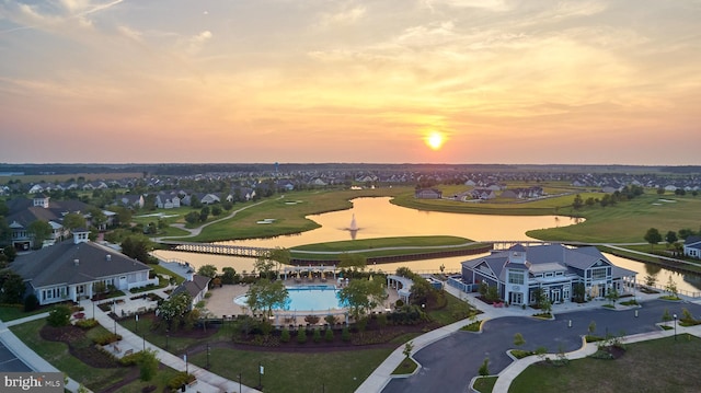 aerial view at dusk featuring a water view and a residential view