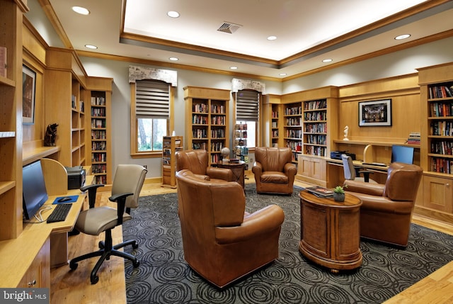 living area featuring ornamental molding, a tray ceiling, visible vents, and wall of books