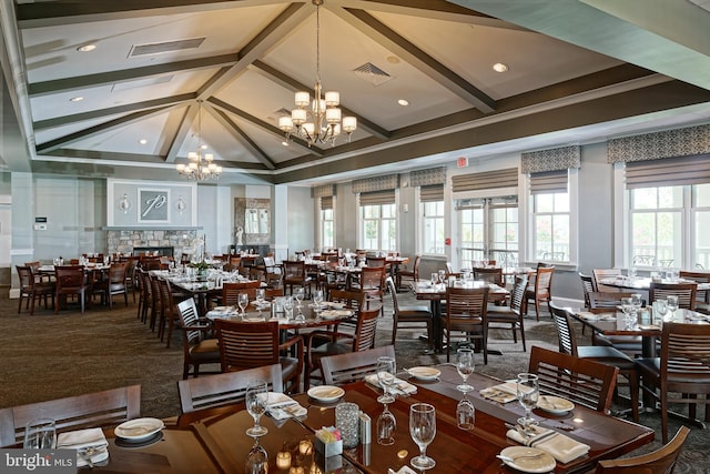 dining area with carpet, vaulted ceiling with beams, a fireplace, visible vents, and an inviting chandelier