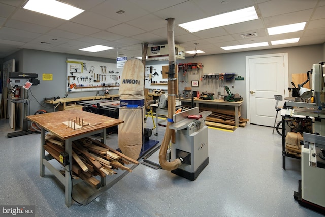 interior space with visible vents, a drop ceiling, a workshop area, and speckled floor