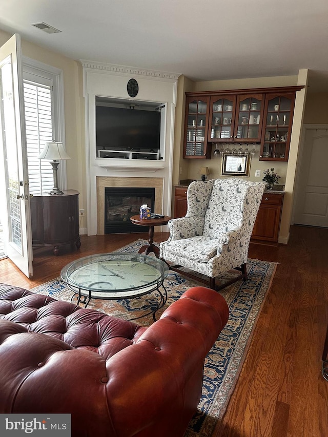 living area with a glass covered fireplace, wood finished floors, and visible vents