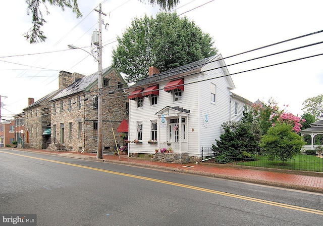 view of front of property featuring a chimney and fence