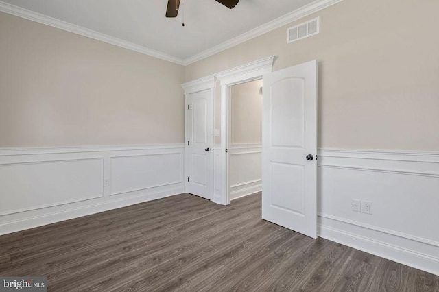 unfurnished bedroom with dark wood-style flooring, visible vents, ornamental molding, a ceiling fan, and wainscoting