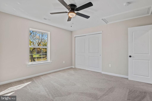 unfurnished bedroom featuring light colored carpet, visible vents, baseboards, a closet, and attic access