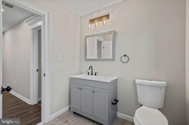 half bathroom featuring toilet, baseboards, visible vents, and vanity