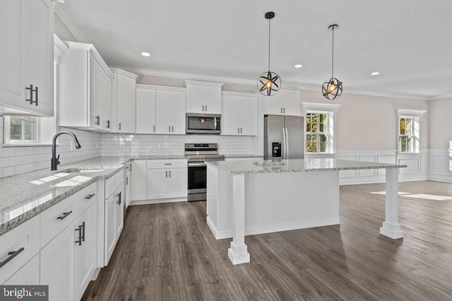 kitchen featuring hanging light fixtures, appliances with stainless steel finishes, white cabinets, and a center island