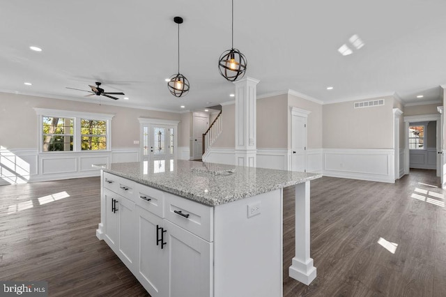 kitchen featuring light stone counters, pendant lighting, visible vents, open floor plan, and white cabinetry