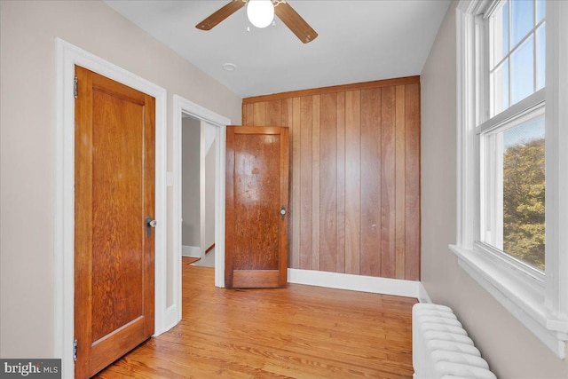 unfurnished room featuring wood walls, radiator heating unit, wood finished floors, and baseboards