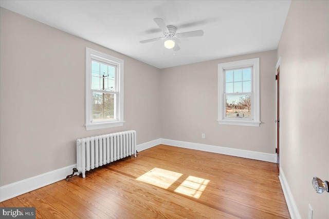 unfurnished room with baseboards, ceiling fan, light wood finished floors, and radiator