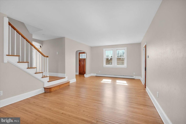 unfurnished living room featuring light wood-type flooring, stairs, baseboards, and baseboard heating