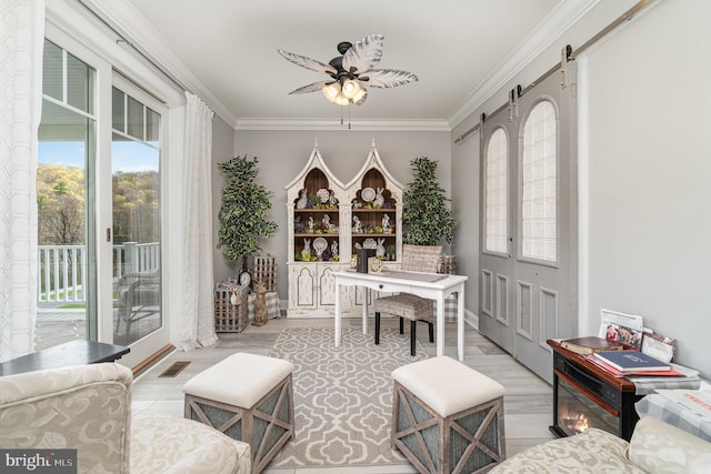 interior space featuring a barn door, visible vents, ceiling fan, and crown molding