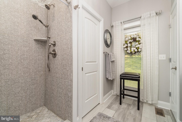 bathroom with a healthy amount of sunlight, visible vents, and tiled shower