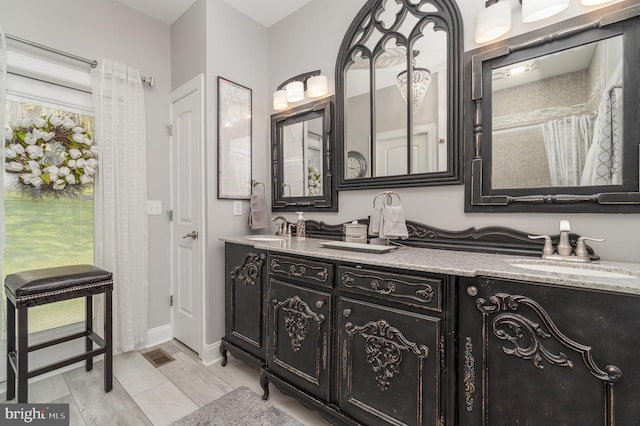 bathroom with double vanity, a sink, visible vents, and baseboards