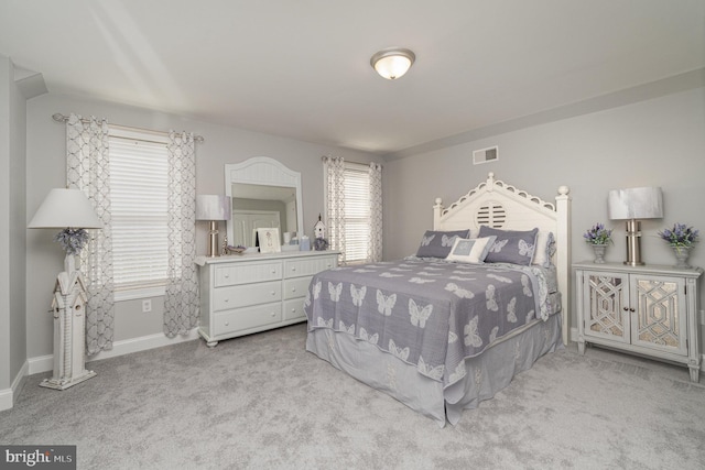 bedroom featuring visible vents, light carpet, and baseboards