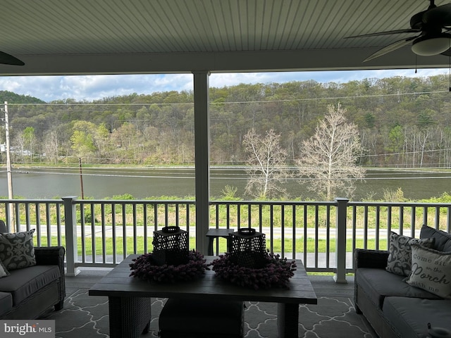 sunroom featuring a water view, ceiling fan, and a view of trees