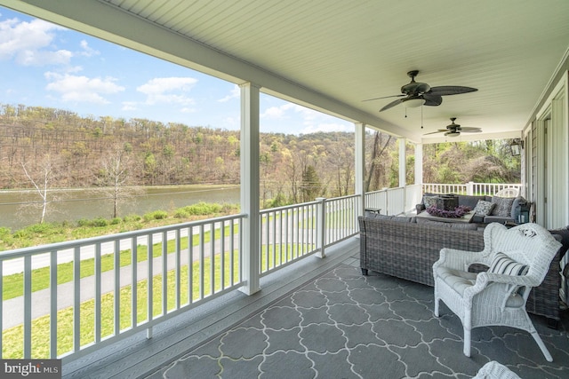 exterior space featuring ceiling fan, an outdoor hangout area, and a view of trees