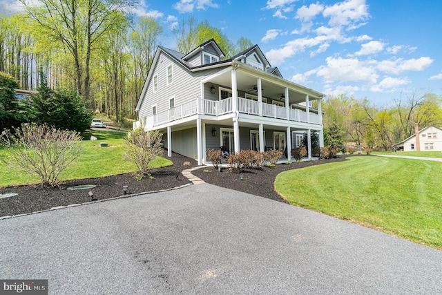 view of front of house featuring a balcony, aphalt driveway, a ceiling fan, and a front yard