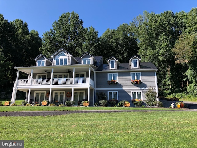 view of front facade featuring a balcony, a ceiling fan, and a front yard