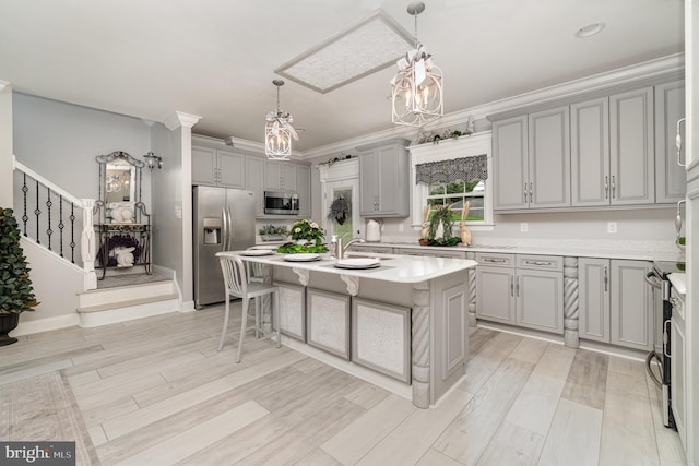 kitchen with a center island with sink, stainless steel appliances, light countertops, a kitchen bar, and pendant lighting