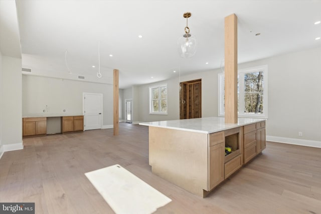 kitchen with pendant lighting, a spacious island, light countertops, open floor plan, and light wood-type flooring