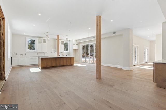 unfurnished living room featuring baseboards, light wood-type flooring, visible vents, and recessed lighting