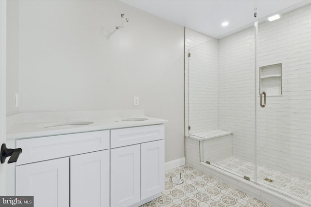 bathroom featuring double vanity, a stall shower, baseboards, and recessed lighting