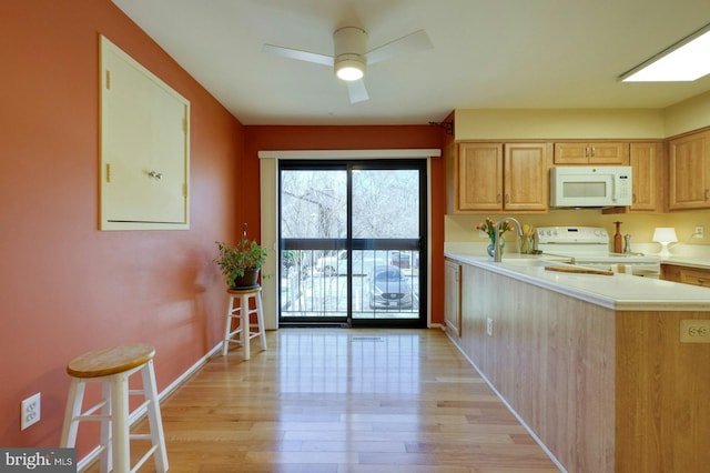 kitchen with white appliances, baseboards, light wood finished floors, a peninsula, and light countertops