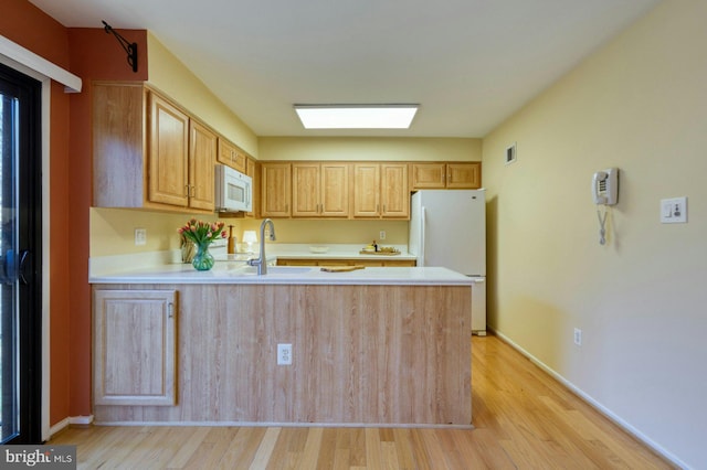 kitchen featuring a sink, white appliances, a peninsula, and light countertops