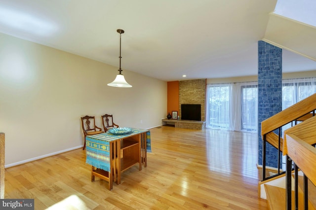 dining space with a fireplace, baseboards, lofted ceiling, and light wood-style floors