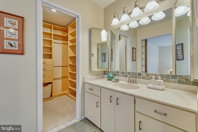 bathroom featuring decorative backsplash, a spacious closet, and vanity