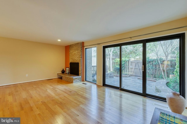 unfurnished living room with light wood-type flooring, visible vents, and a fireplace