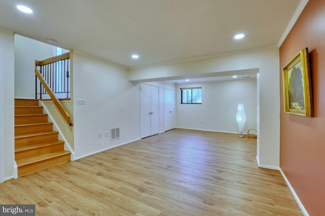 basement featuring visible vents, light wood finished floors, and ornamental molding